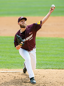 Pitcher throwing baseball in maroon jersey and hat.