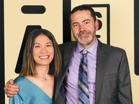 Annie Kuo and Matt Becker stand side by side with their arms around each other, smiling.