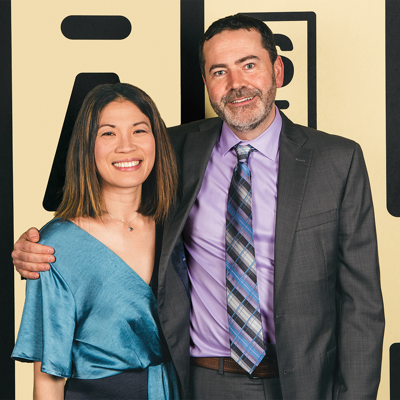 Annie Kuo and Matt Becker stand side by side with their arms around each other, smiling.