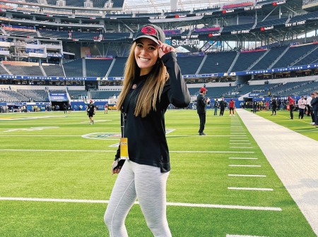 Emma Steinberg poses with her hat on a football field.