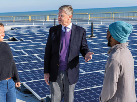 Michael R. Wasielewski stands with two students in front of a large array of solar panels.