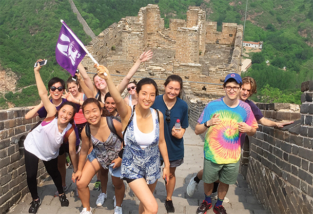 Northwestern students pose on the great wall of China, waving a Northwestern flag.