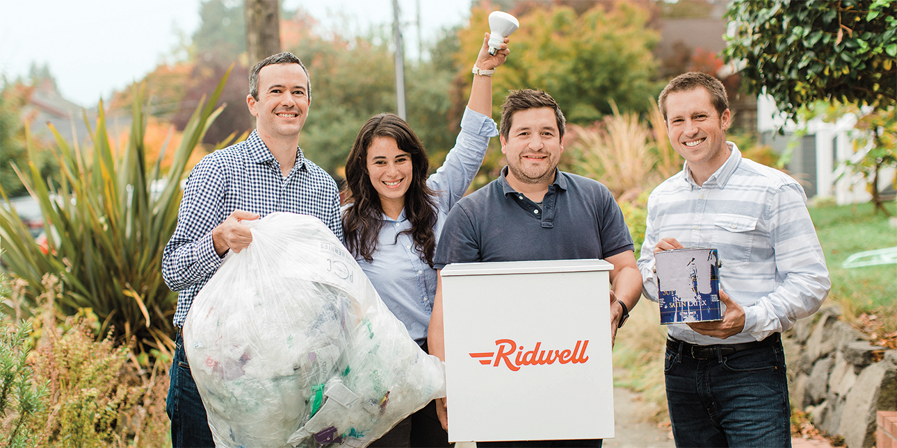 Ridwell founders Ryan Metzger, Aliya Marder, Justin Gough and David Dawson stand outside holding a variety of recyclable items and a Ridwell recycling container.