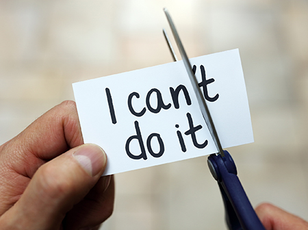 Scissors cutting through a piece of paper that says “I can’t do it.”