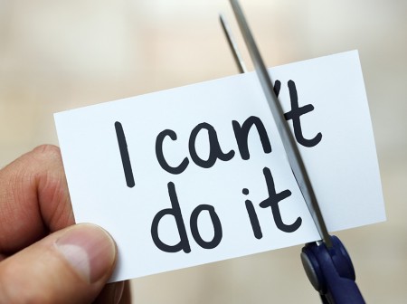 Scissors cutting through a piece of paper that says “I can’t do it.”