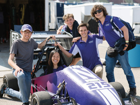 Team smiles around a Northwestern branded race car