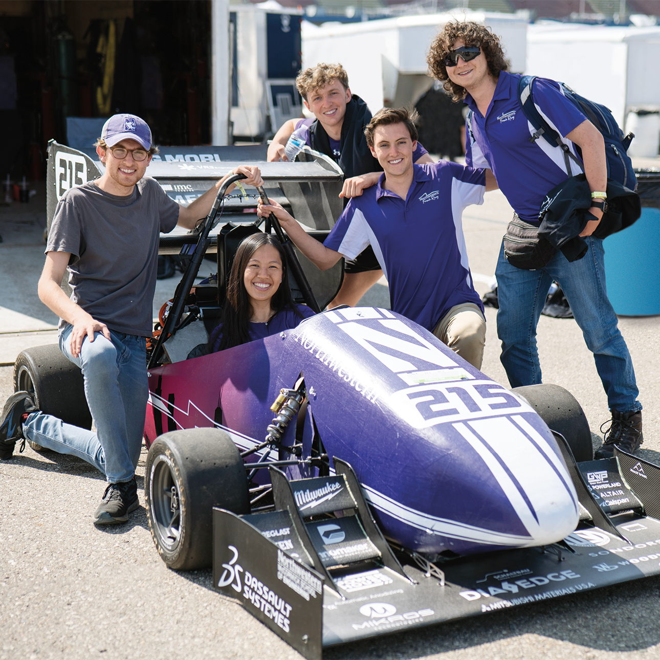 Team smiles around a Northwestern branded race car