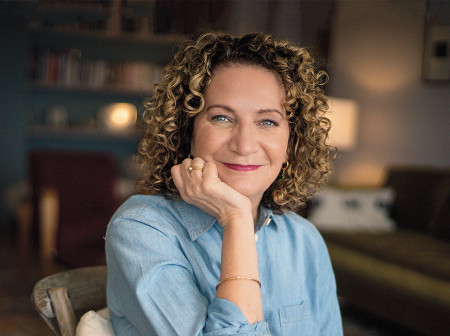 Michelle Lowe sits at a wooden table wearing a light blue button-up shirt.