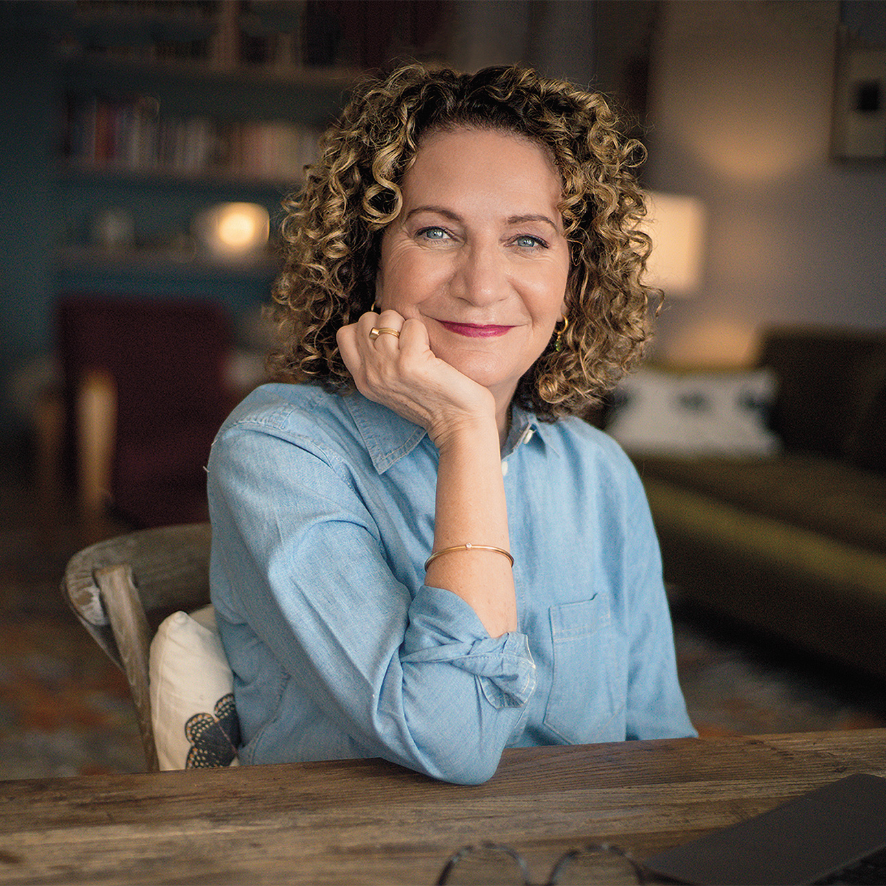 Michelle Lowe sits at a wooden table wearing a light blue button-up shirt.