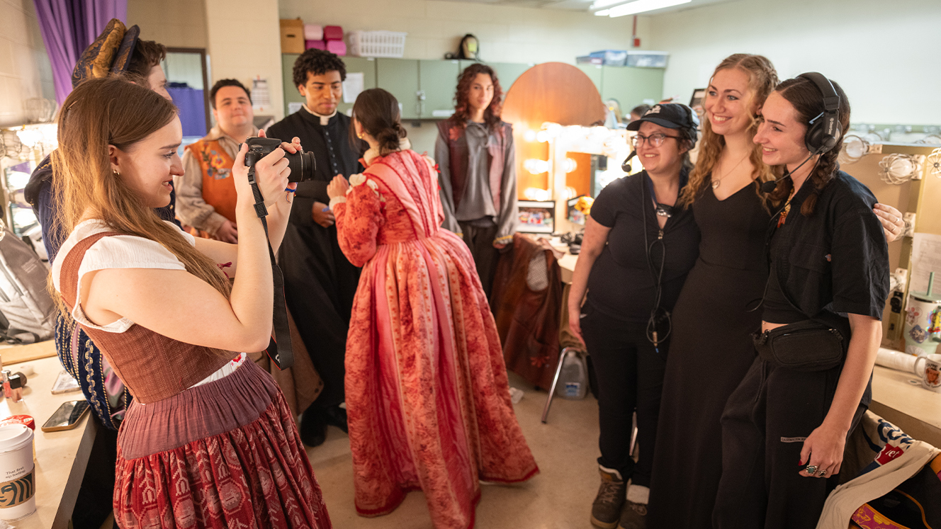 Three people dressed in black and wearing headsets pose for a picture in a dressing room. 