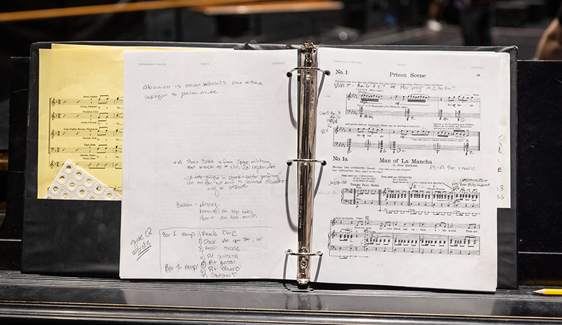 A three-ring binder is propped up on a piano’s music stand. It shows the musical score for the Prison Scene of Man of La Mancha, along with scribbled notes.