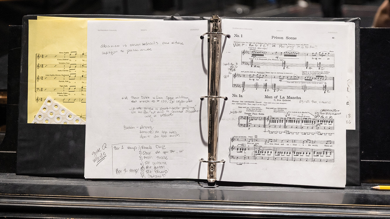 A three-ring binder is propped up on a piano’s music stand. It shows the musical score for the Prison Scene of Man of La Mancha, along with scribbled notes.