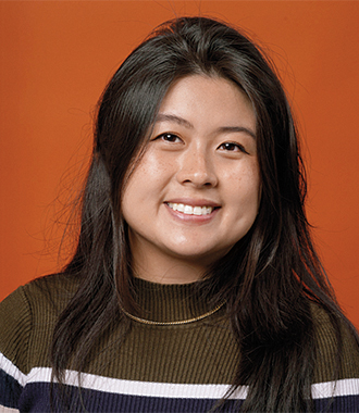 Alissa Zhu smiles for the camera against an orange background