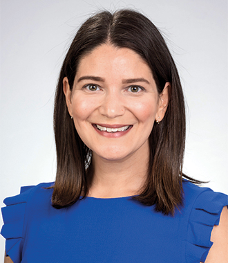 Emily Glazer smiles for the camera wearing a bright blue top