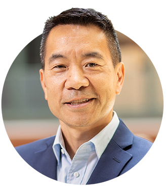 A headshot of Abel Kho in a button-up shirt and blue suit jacket 