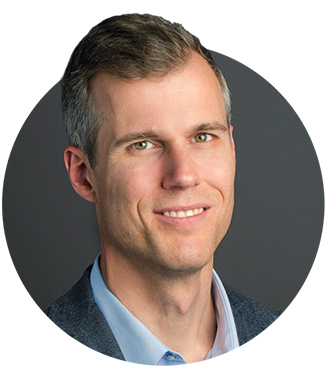 A headshot of Ben Jones in a blue collared shirt and dark jacket 