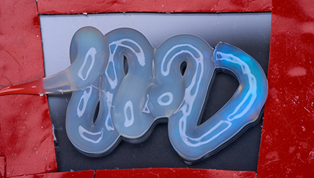 A blue, wavy squirt of gel on a glass slide. 