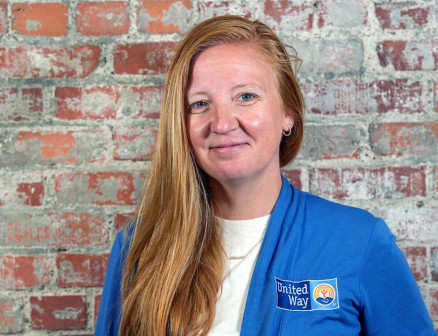 Lauren Kimball in a blue sweater with the United Way of the Midlands logo against a red brick wall.