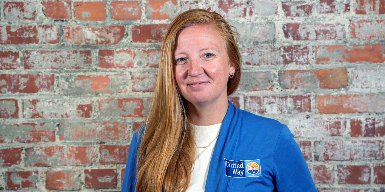 Lauren Kimball in a blue sweater with the United Way of the Midlands logo against a red brick wall.