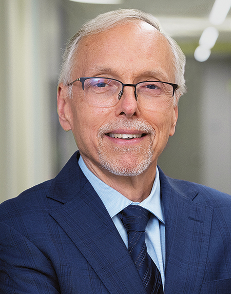 Robert Vassar, wearing a blue suit and glasses, smiles at the camera.
