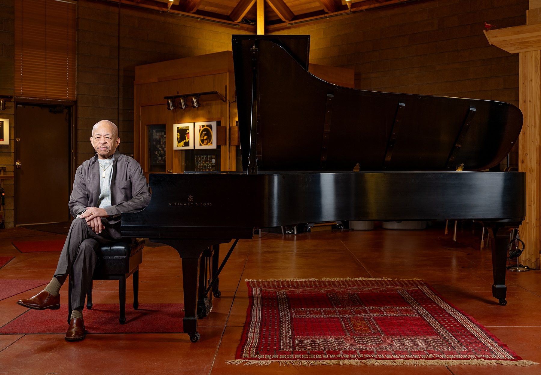 A side profile of Steve Colson, wearing a gray suit, playing on a Steinway grand piano.