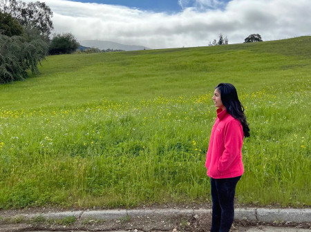 Aanya Dhruv stands next to a large grassy field.