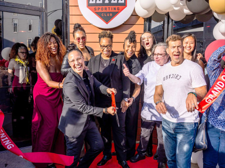 A group of adults smiling and celebrating a ribbon-cutting event for Level Sporting Club