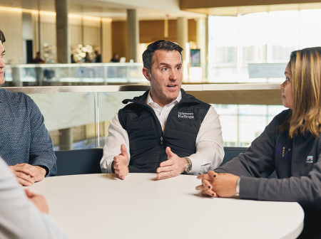 Matt Caldwell and three other people sit and talk at a table in Northwestern’s Global Hub.