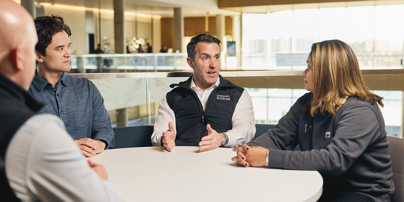 Matt Caldwell and three other people sit and talk at a table in Northwestern’s Global Hub.