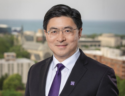 Mung Chiang poses in front of a blurred landscape background. 