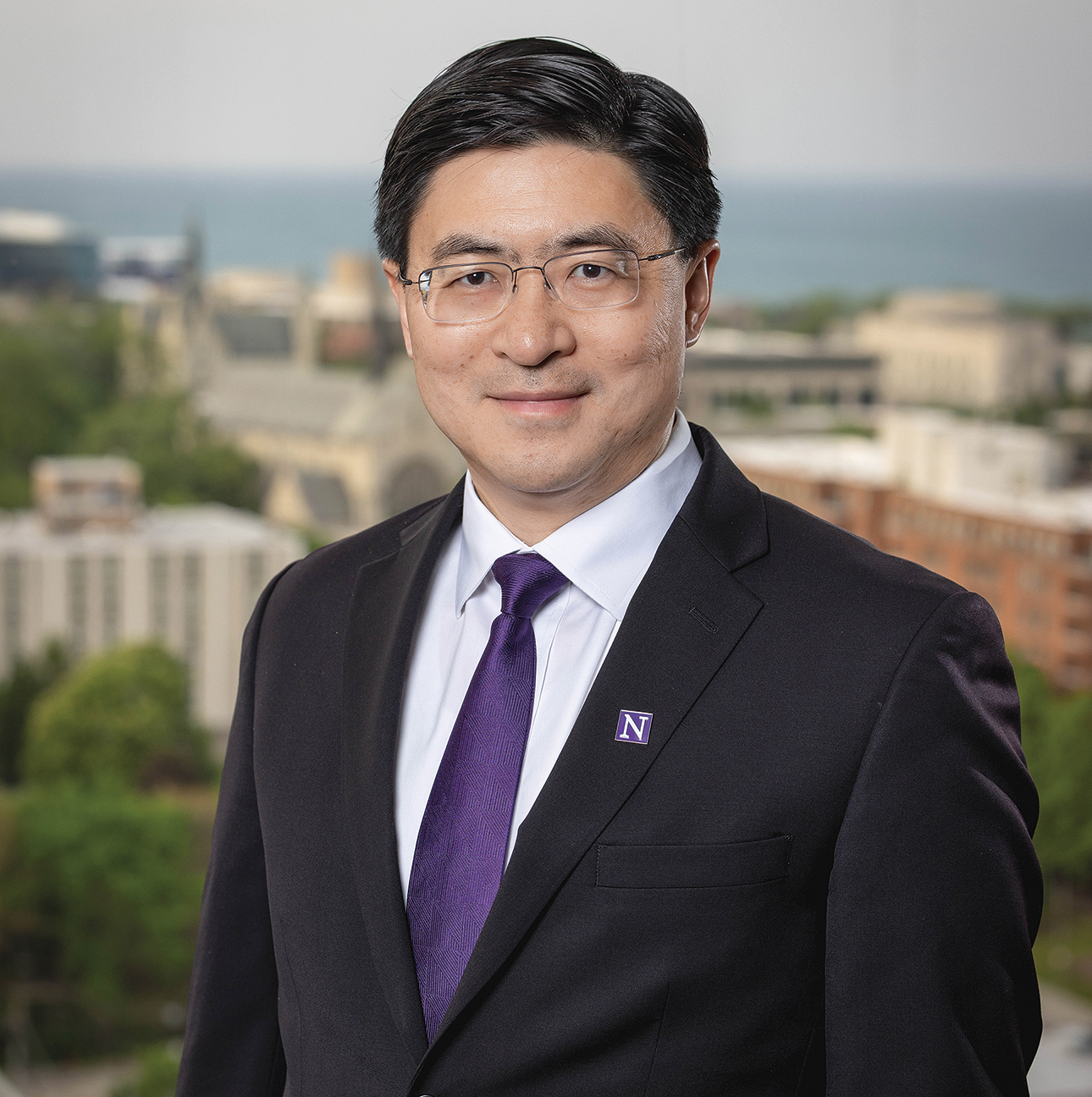 Mung Chiang poses in front of a blurred landscape background. 