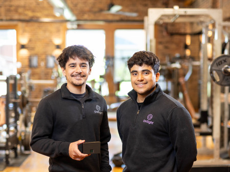 Two men stand in a gym.