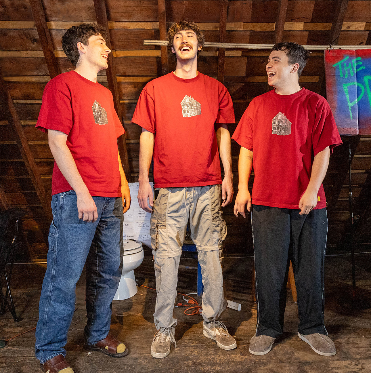 Three men in an attic laugh with each other