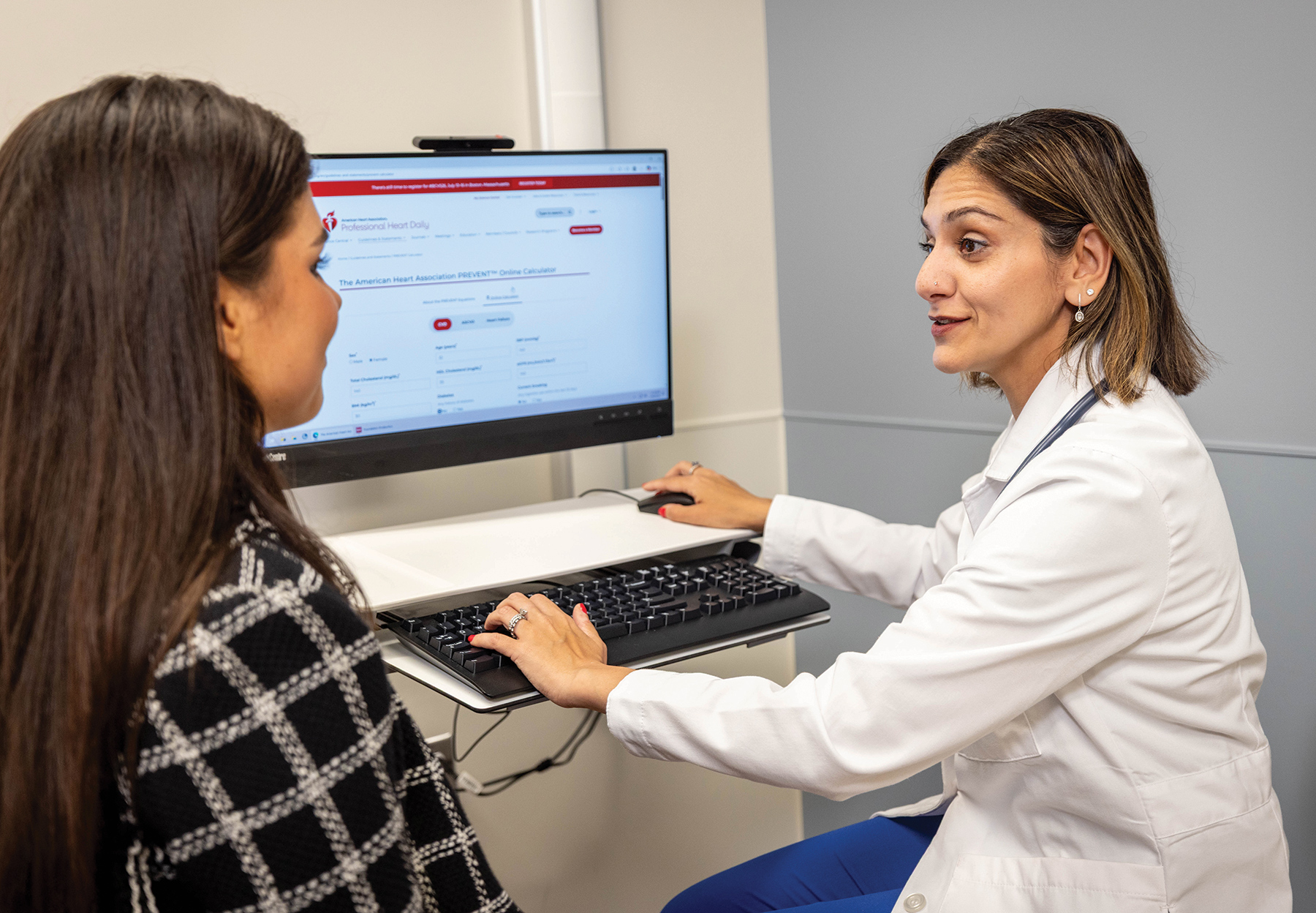 Sadiya Khan speaks to a patient while using the PREVENT tool on a computer.