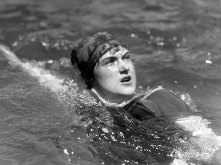 A black-and-white photo of Sybil Bauer swimming the backstroke while wearing a swimming cap.