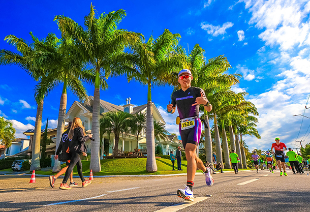 Taeyoung Lee, dressed in a Northwestern running kit, runs down a bright street lined in palm trees.