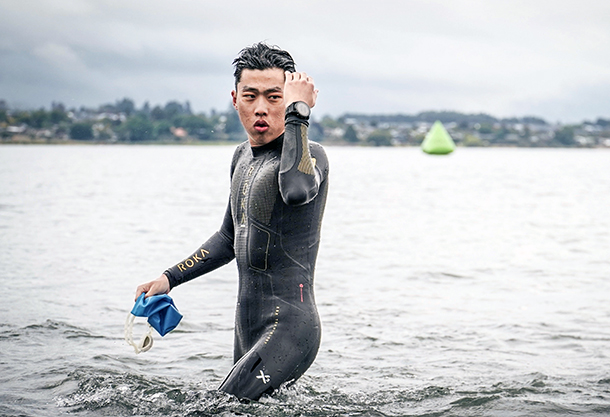 Taeyoung Lee stands in the lake wearing a wetsuit.