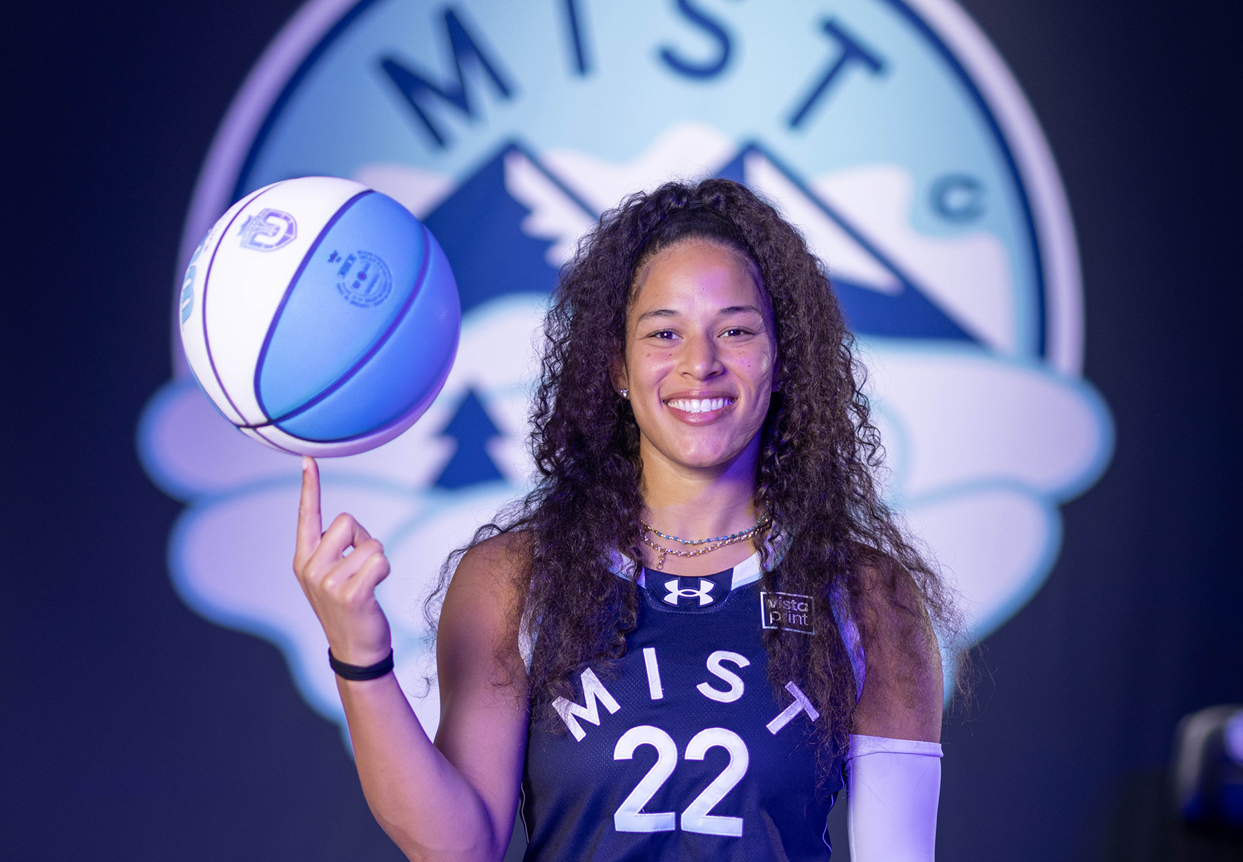 Veronica Burton smiles at the camera, spinning a basketball on her left pointer finger.