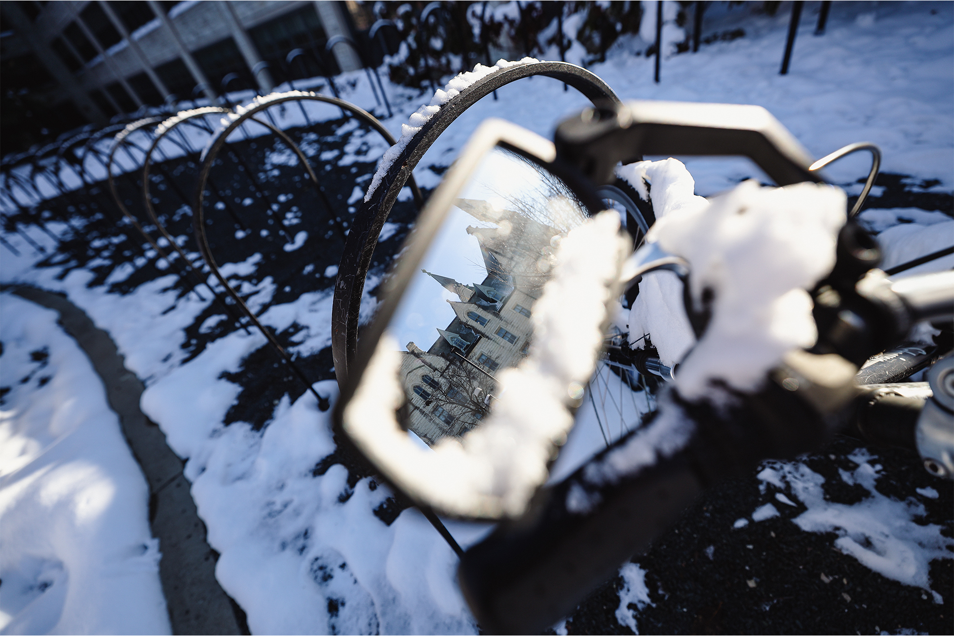 A snow-covered moped mirror shows University Hall.