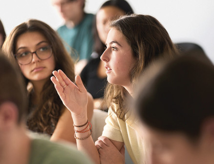 A student speaks as her peers listen inside a classroom.