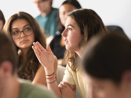 A student speaks as her peers listen inside a classroom.
