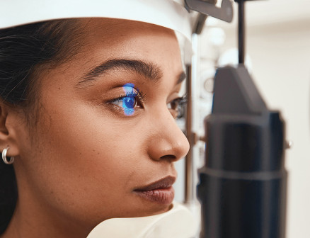 A woman has her eye scanned in a clinic
