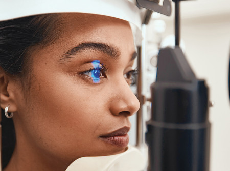 A woman has her eye scanned in a clinic
