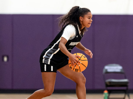 An action shot of Sammy White, wearing a Northwestern basketball uniform, palming a basketball.