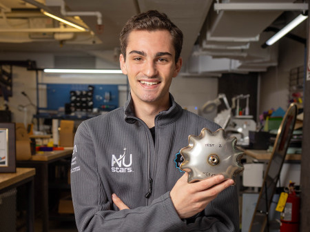 Trevor Abbott holds a piece of his team’s inflatable system. Additional pieces of the system sit on a table in front of him.