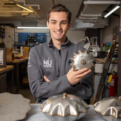 Trevor Abbott holds a piece of his team’s inflatable system. Additional pieces of the system sit on a table in front of him.